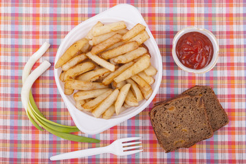 Fried potatoes in a plate on a tablecloth.