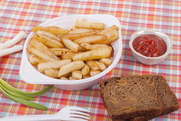 Fried potatoes in a plate on a tablecloth.