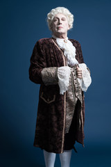 Retro baroque man with white wig standing and looking arrogant.