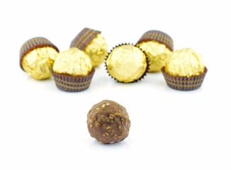chocolate balls with almond in a gold foil paper on white backgr