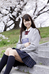 Obraz premium 桜の木の下で勉強する女子高生