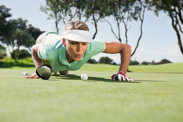 Female golfer blowing her ball on putting green