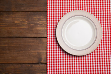 Plate on wooden table with red checked tablecloth