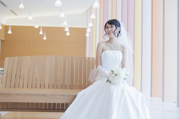 教会で座るブーケを持ったウエディングドレス姿の女性