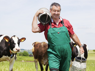 farmer with milk churns at his cows