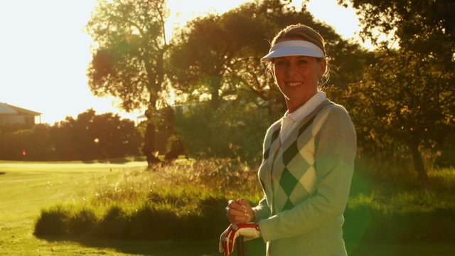 Happy woman smiling at camera on the golf course