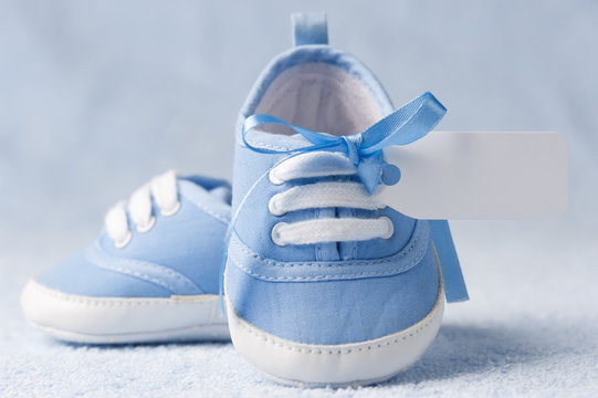 Little baby booties with a tag on a blue background