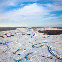 Top view of the snow-covered lowland of the forest river