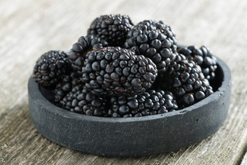 bowl of fresh blackberries on wooden background
