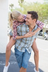 Naklejka premium Young hip man giving his blonde girlfriend a piggy back