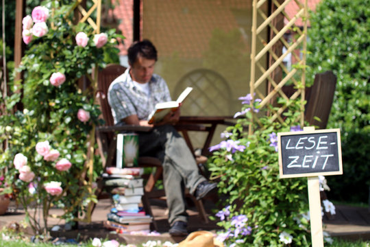 Schild "Leselzeit" mit lesenden Mann im Garten