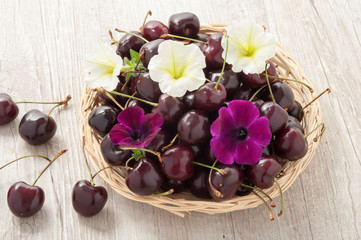 Cestino in vimini con ciliege e fiori freschi