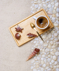 Cup of coffee on the sea pebbles on beach party