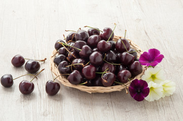 Cestino in vimini con ciliegie e fiori freschi