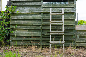 Fototapeta na wymiar Weathered wooden ladder leaning on wooden slats