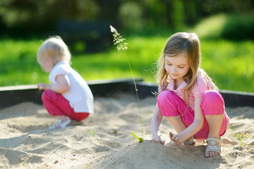 Two little sisters playing in a sandbox