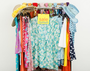 Cute summer outfits displayed on hangers with a big sale sign.