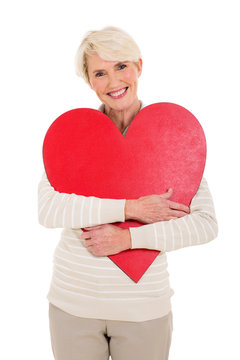 mid age woman hugging red heart shape
