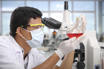 Chemist holding sample of liquid in laboratory