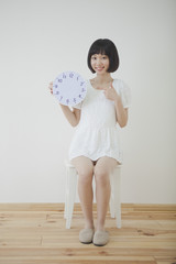 椅子に座って時計を持つ女性