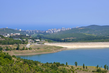 lake with hills near the town on a summer day