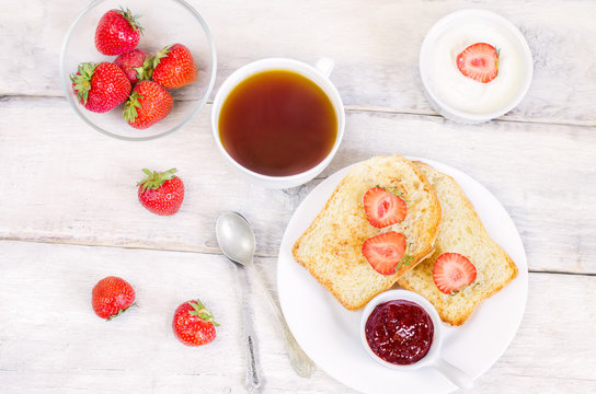 breakfast with fresh toasts, strawberries and strawberry jam