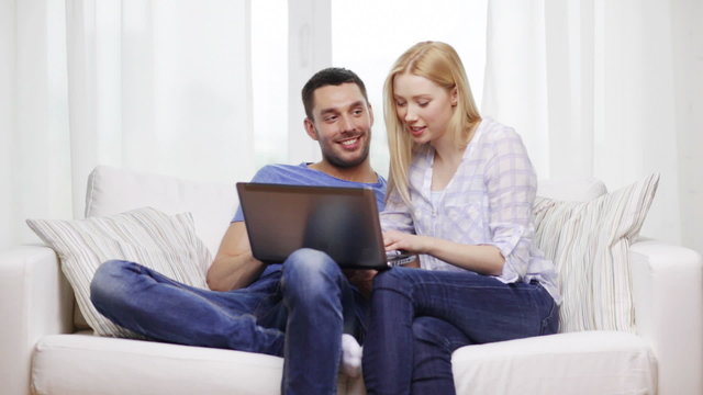 smiling couple with laptop computer at home