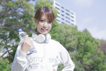 公園でペットボトルを持ってヘッドフォンをする女性