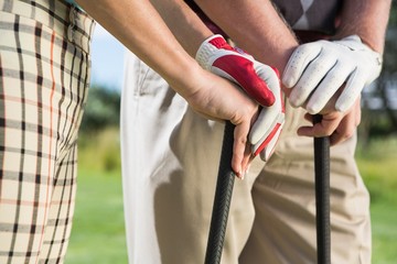 Golfing couple standing holding their clubs