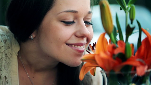 Happy young woman smelling beautiful colorful flowers