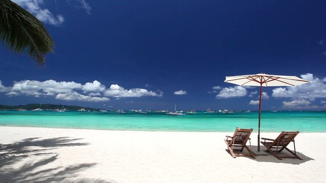 Sun umbrellas and beach chairs on coastline with white sand. Bor