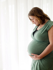 Pregnant young woman looking at her belly