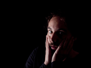 Low key image of a bearded man with shocked expression