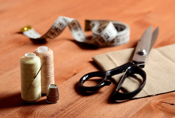 Close-up sewing tools on wooden background, vintage style