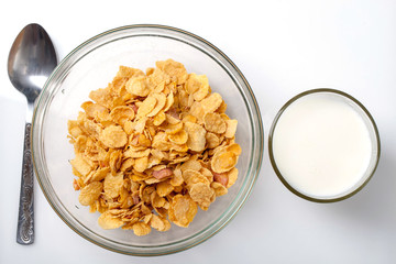 bowl of cold cereal, glass of milk and spoon on white background