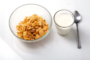 bowl of cold cereal, glass of milk and spoon on white background