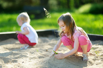 Two little sisters playing in a sandbox