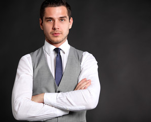 Handsome young business man standing on black background 