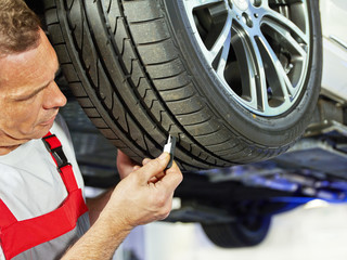 Car mechanic checks the tread pattern of a tire