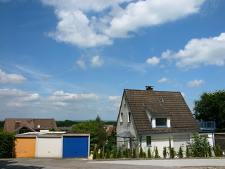 Bunte Garagentore und ein Einfamilienhaus mit Spitzgiebel bei Sonnenschein in Oerlinghausen bei...