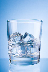 Glass of water with ice on a blue background