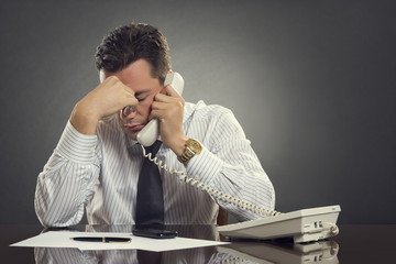 Overwhelmed  businessman with headache speaking on phone