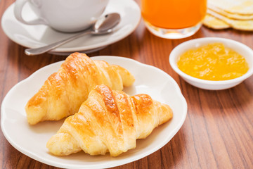 Croissants, coffee cup and juice on wooden table