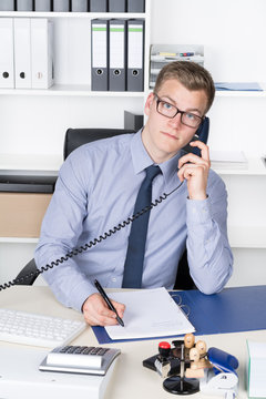 Mann telefoniert und macht dabei Notizen