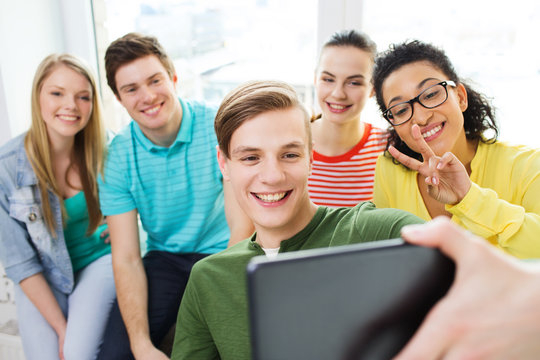 smiling students making picture with tablet pc