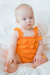 Blond baby girl with blue eyes in a romper