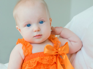 Blond baby girl with blue eyes in a romper