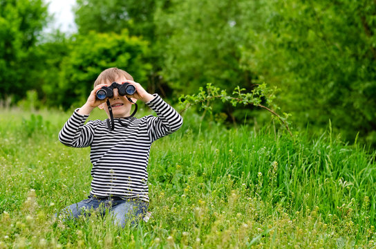 Little boy looking at the camera with binoculars