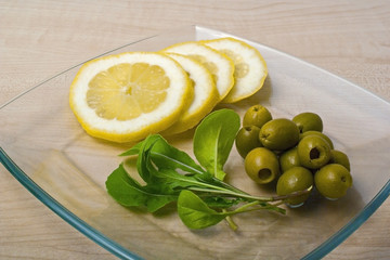 arugula, lemon and olives on a plate on the table