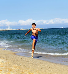 Boy running on the sea beach on summer holidays